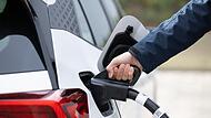 Ein Mann steckt ein Ladekabel in ein Elektroauto