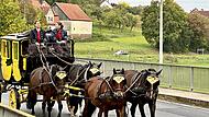 Die Leinen fest in weiblicher Hand: die Postkutsche mit den Kutscherinnen Yvonne Körner (links) und Paulina Klöffel auf der Brücke vor Schloss Aschach.