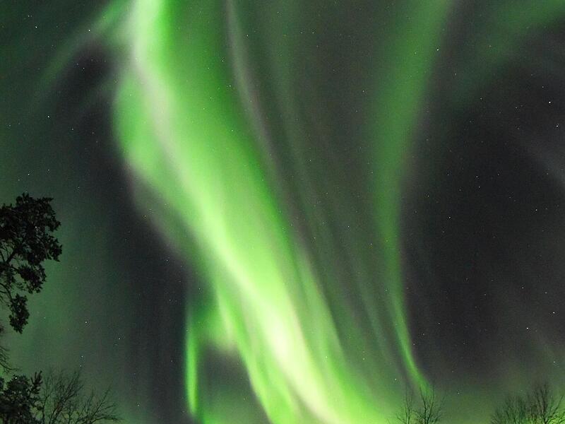 Wie eine riesige gr&uuml;ne Flamme lodert das Nordlicht &uuml;ber dem Ferienhaus in Lappland.