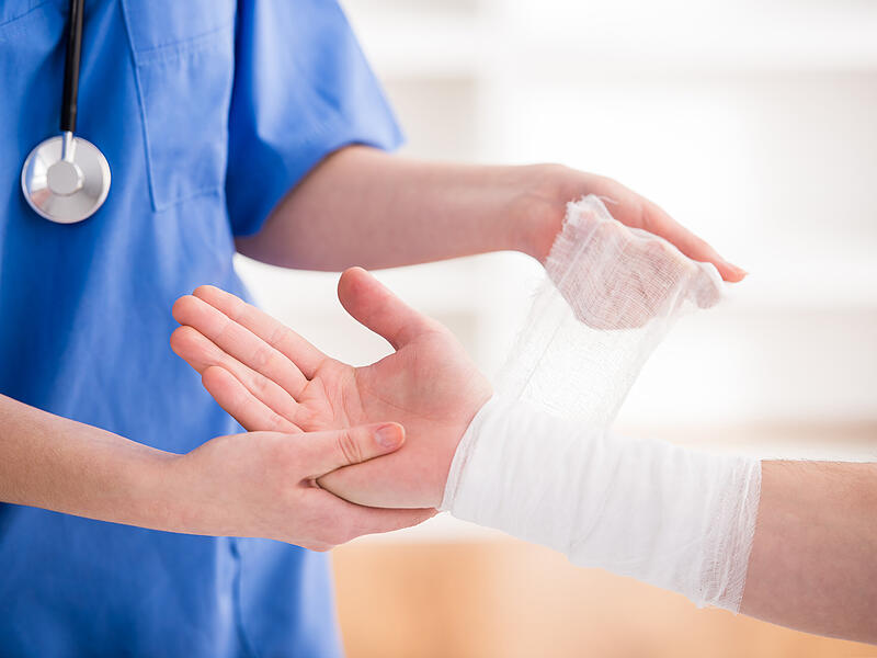 Eine Pflegekraft legt einer Patientin einen Verband an.