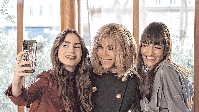 Die Schauspielerinnen Lily Collins (links) und Thalia Besson (rechts) mit Brigitte Macron. Die Ehefrau des franz&ouml;sischen Pr&auml;sidenten hat einen Auftritt in der Netflix-Serie &bdquo;Emily in Paris&ldquo;. Emily ist k&uuml;nftig in Rom.