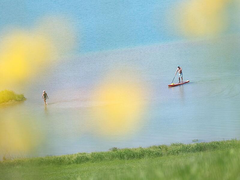 Ein SUP-Fahrer fährt auf dem Forggensee. Ein SUP-Fahrer fährt auf dem Forggensee.