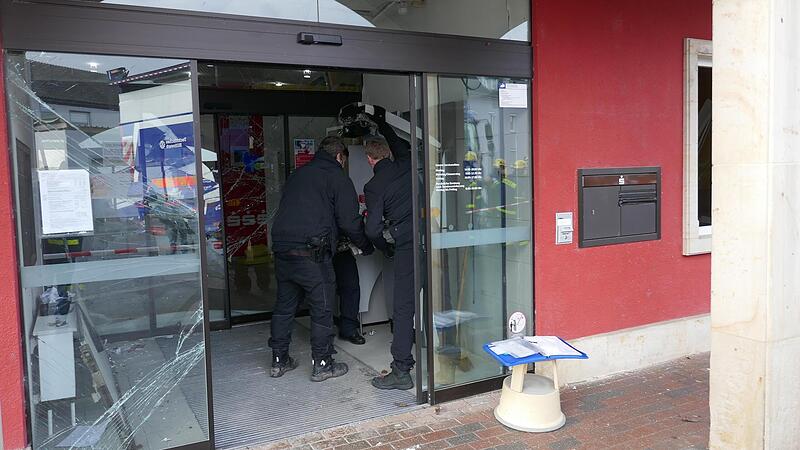Polizeibeamte nehmen am Tatort den gesprengten Automaten in Augenschein.