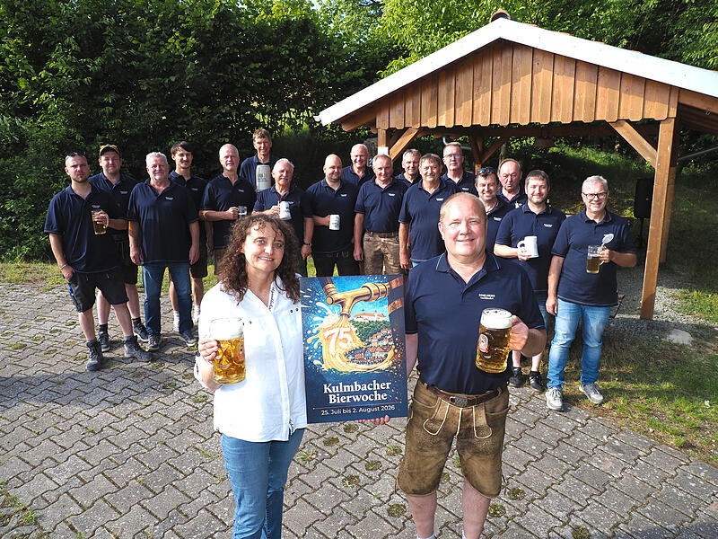 Der Stammtisch "Zur Hilde Marua&ldquo; st&ouml;&szlig;t gemeinsam mit seinem Mitglied Rolf E. Huber und Birgit Reichardt von der Kulmbacher Brauerei auf das Siegerplakat der 75. Kulmbacher Bierwoche an.