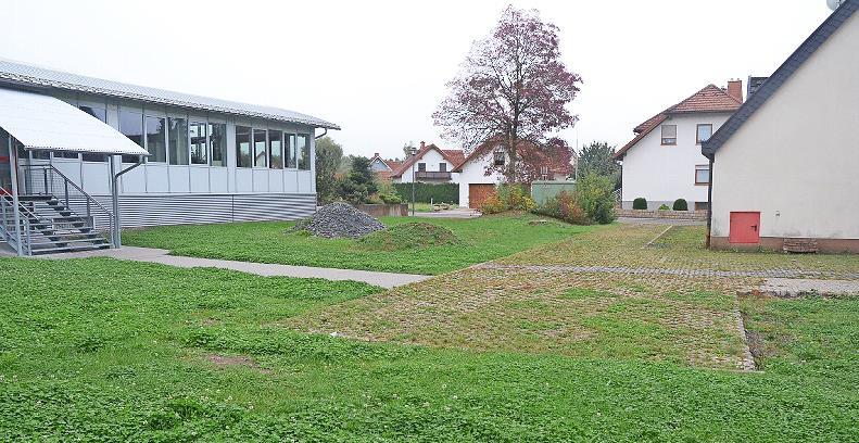 Diese Fläche zwischen bisherigem Feuerwehrhaus mit Schulungsraum (rechts) sowie neuem Feuerwehrhaus (links) wird 19 Parkplätze erhalten und dabei wird viel Grünfläche rundherum bis zur Rathausstraße (im Hintergrund) neu gestaltet.