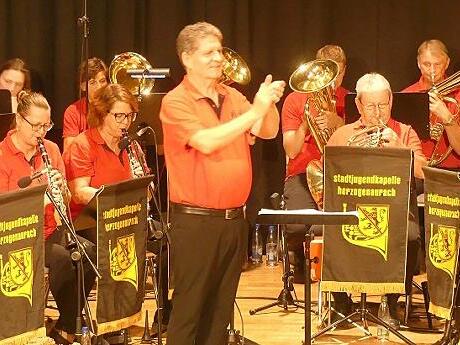 Die Ehemaligen der Stadtjugendkapelle auf der Bühne des Vereinshauses mit Rainer Wanjelik als Dirigent, der die Zuhörer mit Mitklatschen animiert