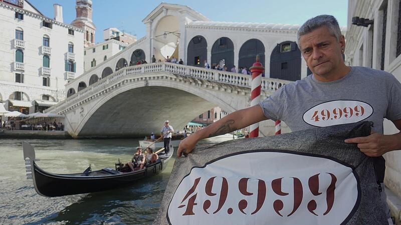 Matteo Secchi vor der Ponte di Rialto. Mit Plakaten versuchten Venezianer darauf aufmerksam zu machen, dass die Einwohnerzahl der Touristenstadt mittlerweile unter 50.000 gesunken ist.