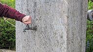 Kein Tropfen kommt: Eine Frau dreht vergeblich am Hahn der Zapfstelle in Zahlbach. (Symbolfoto)