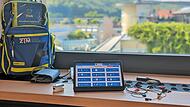 Auf dem Tablet ist die Oberfläche der App Mia zu sehen. Im nebenstehenden Rucksack befinden sich die Geräte, die MFAs beim Hausbesuch benötigen. Moderne Geräte lassen sich via Bluetooth mit dem Tablet verbinden.