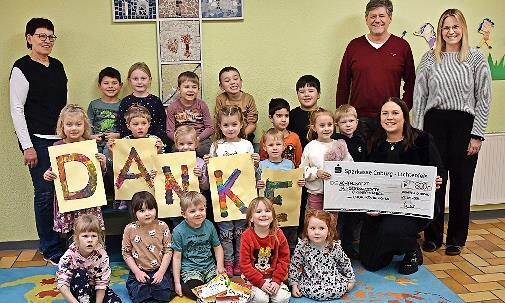 Zweite Vorsitzende des Route-Chores, Svenja Weid, (knieend, re.) und stellvertretender Chorleiter Uwe Stegner (hinten, Zweiter v.r.) bei der &Uuml;bergabe des Schecks mit der Geldspende. Dar&uuml;ber freuen sich die Kinder und Kita-Leiterin Daniela Rech (re...