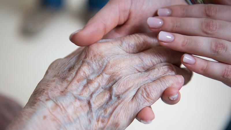Pflegerin hält Hand einer Seniorenheim-Bewohnerin Pflegerin hält Hand einer Seniorenheim-Bewohnerin