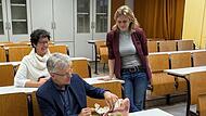 Die Lehrer Rolf Kraus (v.), Ricarda Schilling (h.l.) und Amancay Greulich vom Gymnasium Herzogenaurach in einem Stufensaal.