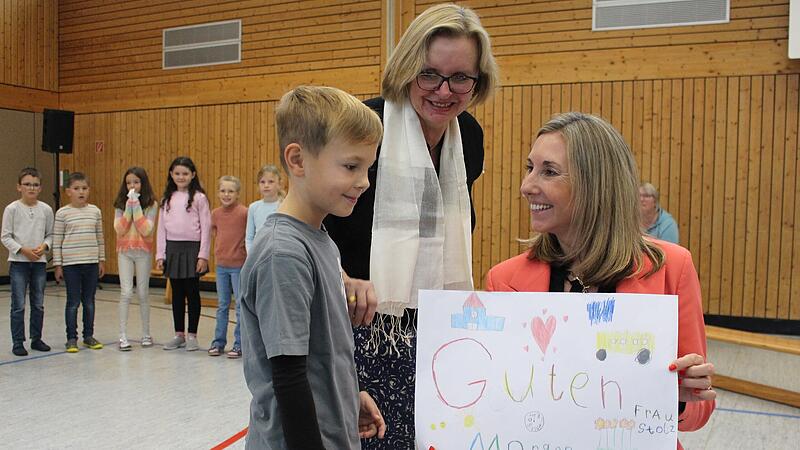 Schüler und Schulleiterin Ulla Farkas (mitte) begrüßen Kultusministerin Anna Stolz (rechts) in der Grundschule in Zeitlofs.