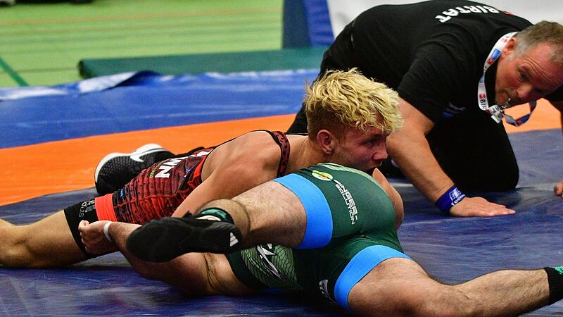 Bastian Hoffmann (oben) drückt den Nürnberger Hamed Kiani auf die Schultern. Mattenleiter Andre Schedler beobachtet das genau.