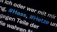 Auf dem Bildschirm eines Smartphones sieht man die Hashtags (#) Hass und Hetze in einem Twitter-Post. Ein Mann aus Erlangen steht nun wegen Hetze im Internet vor Gericht.