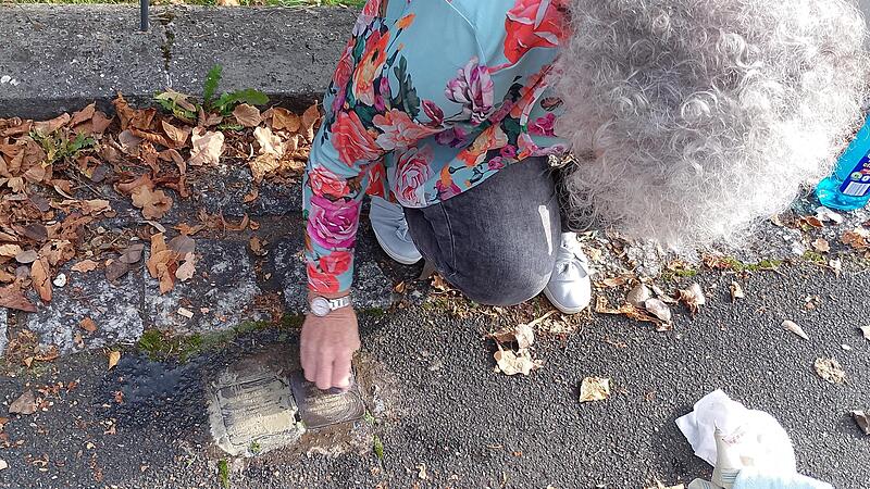 Eine B&uuml;rgerin reinigt die Stolpersteine in Sassanfahrt, die an die j&uuml;dische Familie von Samuel und Minna Merel erinnern.