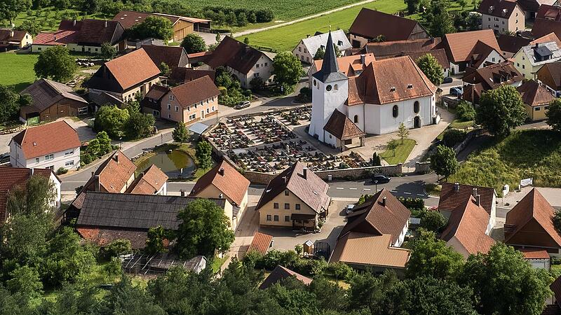 Ausschnitt aus einer Luftaufnahme von Moggast: Der Dorfweiher befindet sich links vor der Friedhofsmauer.Forchheim & Fränkische Schweiz