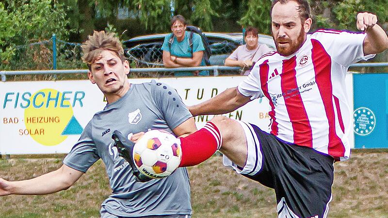 Der Neuenmarkter Spielertrainer André Haack (rechts) klärt mit hohem Bein vor deinem Donndorfer.