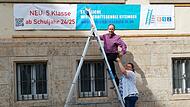 Steffen Prepens und Bettina Schütz machen mit einem großen Banner auf das neue Angebot aufmerksam: Die staatliche Wirtschaftsschule Kitzingen kann nun ab der 5. Klasse besucht werden.