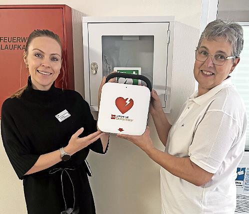 Die Vorsitzende des AWO-Ortsvereins, Kerstin Ziegler (rechts), übergibt den AED an die Einrichtungsleitung des Willy-Brandt-Hauses, Lisa Böhme.