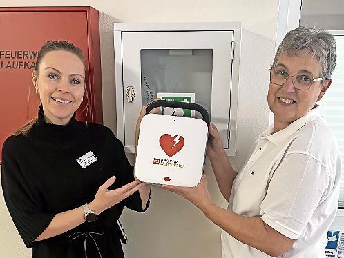 Die Vorsitzende des AWO-Ortsvereins, Kerstin Ziegler (rechts), übergibt den AED an die Einrichtungsleitung des Willy-Brandt-Hauses, Lisa Böhme.