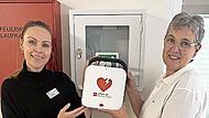 Die Vorsitzende des AWO-Ortsvereins, Kerstin Ziegler (rechts), übergibt den AED an die Einrichtungsleitung des Willy-Brandt-Hauses, Lisa Böhme.