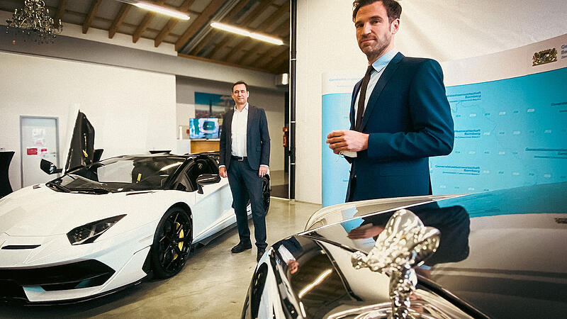 Der Bayerische Justizminister Georg Eisenreich (links) und Staatsanwalt Dr. Nino Goldbeck mit einem beschlagnahmten Rolls-Royce Phantom und einem Lamborghini Aventador.