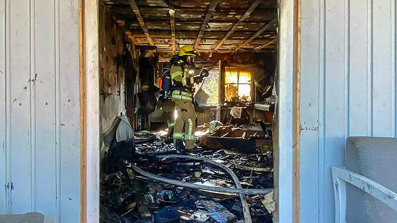 Eine Feuerwehr-Einsatzkraft steht in dem v&ouml;llig ausgebrannten Wohnzimmer der Familie Pertsch in Untersiemau.