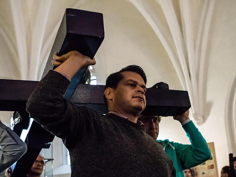 Choristen tragen bei einer Probe ein Kreuz in die Morizkirche.