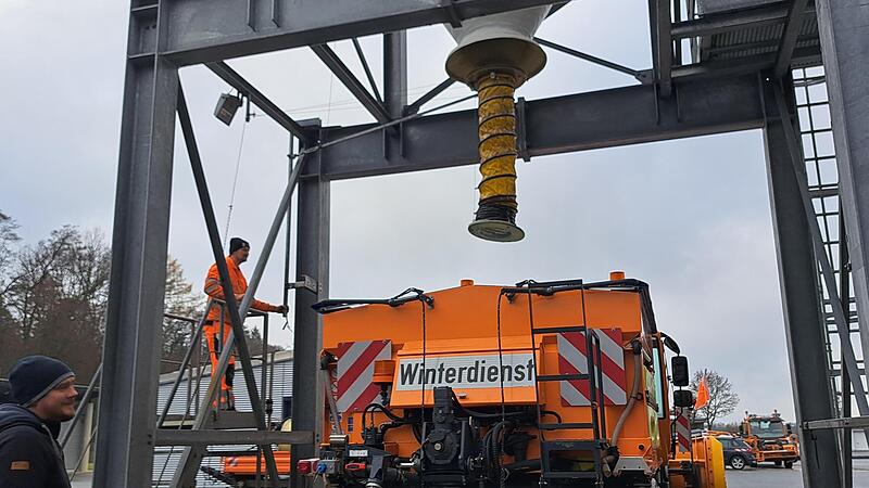 Steffen Lieb sieht zu, wie Gabriel Brehm im Kreisbauhof bei Memmelsdorf ein Winterdienstfahrzeug befüllt.