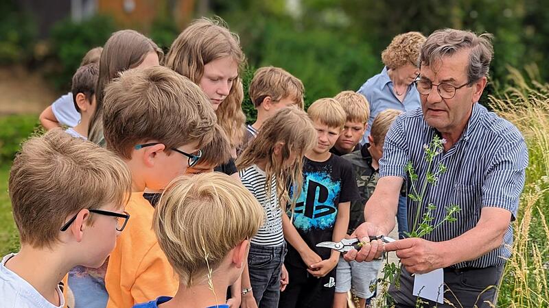 Wolfgang Brascheid zeigt den Melkendorfer Grundsch&uuml;lern, wie sie die Wildblumen genau bestimmen k&ouml;nnen.