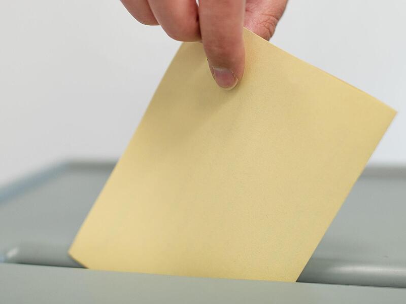 Ein Stimmzettel wird in eine Wahlurne geworfen. In Bayern wird besonders oft von der M&ouml;glichkeit eines B&uuml;rgerentscheids Gebrauch gemacht. Das w&uuml;rde Ministerpr&auml;sident S&ouml;der gern &auml;ndern.