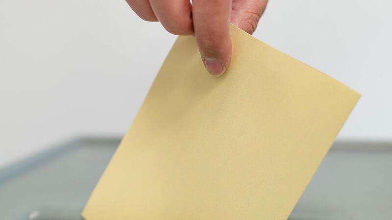 Ein Stimmzettel wird in eine Wahlurne geworfen. In Bayern wird besonders oft von der Möglichkeit eines Bürgerentscheids Gebrauch gemacht. Das würde Ministerpräsident Söder gern ändern.