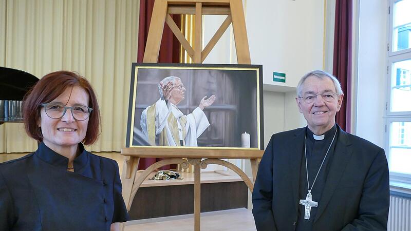 Elke V&ouml;lkl &uuml;bergab jetzt Erzbischof em. Ludwig Schick das Gem&auml;lde, das die Bischofsgalerie im Bistumshaus St. Otto vervollst&auml;ndigt.