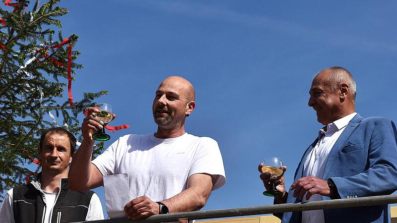 Vom Ger&uuml;st aus sprach Zimmermeister Adrian Kursoni (Mitte) im Beisein seiner Mitarbeiter sowie von B&uuml;rgermeister Robert H&uuml;mmer (rechts) und den Feuerwehrkommandanten von Str&ouml;ssendorf den Richtspruch.