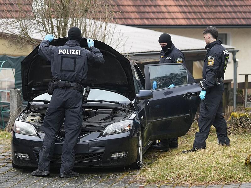 Polizeibeamte durchsuchen w&auml;hrend der Razzia in Pottenstein ein auf dem Grundst&uuml;ck abgestelltes Auto.