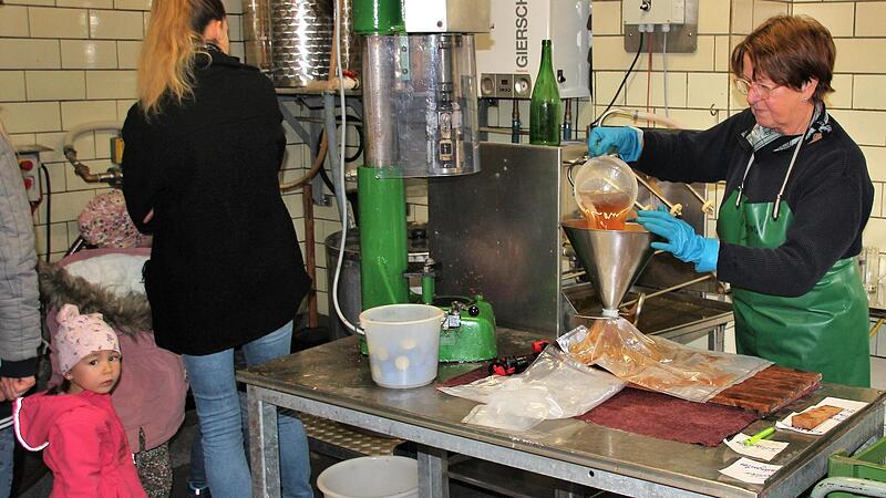 Kindergartenkinder aus Ludwigsstadt erfahren, wie der Apfelsaft gepresst und von Ellen Erhard (rechts) abgefüllt wird.