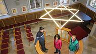 Drei Christen, die sich stark für die Erinnerung an jüdisches Leben in Ermreuth eingesetzt haben und einsetzen: Franz Renker, Rajaa Nadler und Gerhard Maier (von links) stehen in der Synagoge Ermreuth auf dem Almemor.Forchheim & Fränkische Schweiz