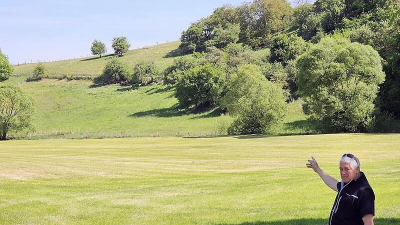 Zweiter B&uuml;rgermeister Reinhold Klein zeigt vom Standort, an dem das Video am Hohnh&auml;user See aufgenommen wurde, in Richtung der Schafweide am Hang unterhalb der B&uuml;sche, wo der Wolf umhergestrichen sein soll.