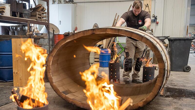 B&uuml;ttner Tobias Schween von der B&uuml;ttnerei A&szlig;mann platziert zum Ausfeuern ein Fass &uuml;ber Feuerschalen. Durch die Hitze wird die Spannung aus dem Holz abgebaut, das zuvor mit Wasserdampf in Form gebracht wurde.