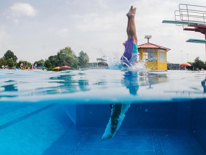 Schwimmer springt vom Sprungturm ins Wasser Symbolbild