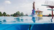 Schwimmer springt vom Sprungturm ins Wasser Symbolbild