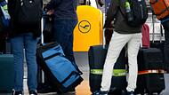 Passagiere warten an einem Check-In-Schalter der Lufthansa