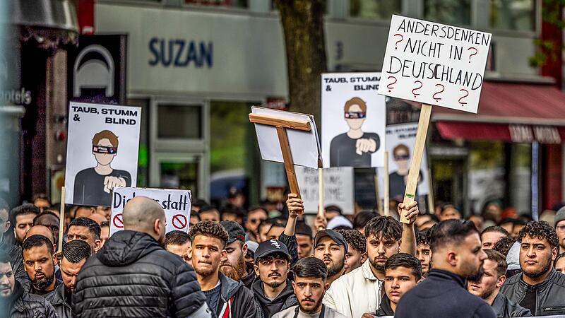 Teilnehmer einer Islamisten-Demo halten ein Plakat mit der Aufschrift &bdquo;Andersdenken? Nicht in Deutschland&ldquo; in die H&ouml;he.
