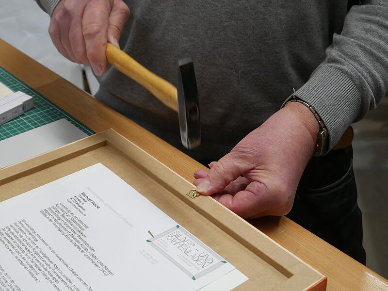 Mit dem Hammer schlägt Michael Back die Befestigung in den Rahmen. Mit dem Hammer schlägt Michael Back die Befestigung in den Rahmen.