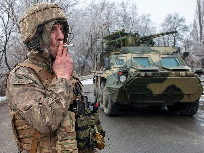 Ein ukrainischer Soldat raucht während seines Einsatzes eine Zigarette neben einem gepanzerten Fahrzeug. Russische Truppen haben den erwarteten Angriff auf die Ukraine gestartet und drangen in die Hauptstadt vor.
