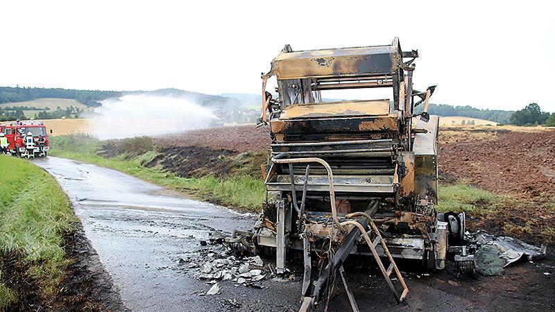 Die Strohballenpresse brannte v&ouml;llig aus. Im Hintergrund ist das bereits umgepfl&uuml;gte Feld zu sehen, das von einem Landwirt bew&auml;ssert wird.