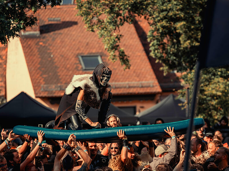 Ein Mitglied der Band Manntra beim Crowdsurfen einmal anders-mit Surfbrett.