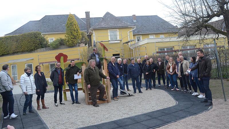 Vertreter des Marktgemeinderates, der Kirchenverwaltung, Kindergartenleitung, Architekturbüro Schöttner besichtigte mit Bürgermeister Stefan Heinlein (rechts) den neu geschaffenen Kinderspielplatz, im Hintergrund das Gebäude der Krippenkinder.