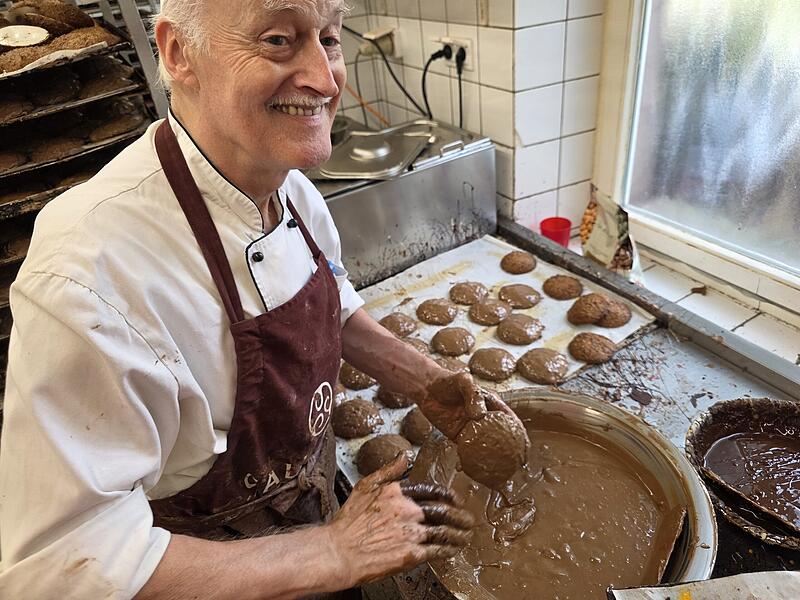 Ein Mitarbeiter der B&auml;ckerei D&uuml;ll bestreicht die Lebkuchen von Hand mit Schokolade.